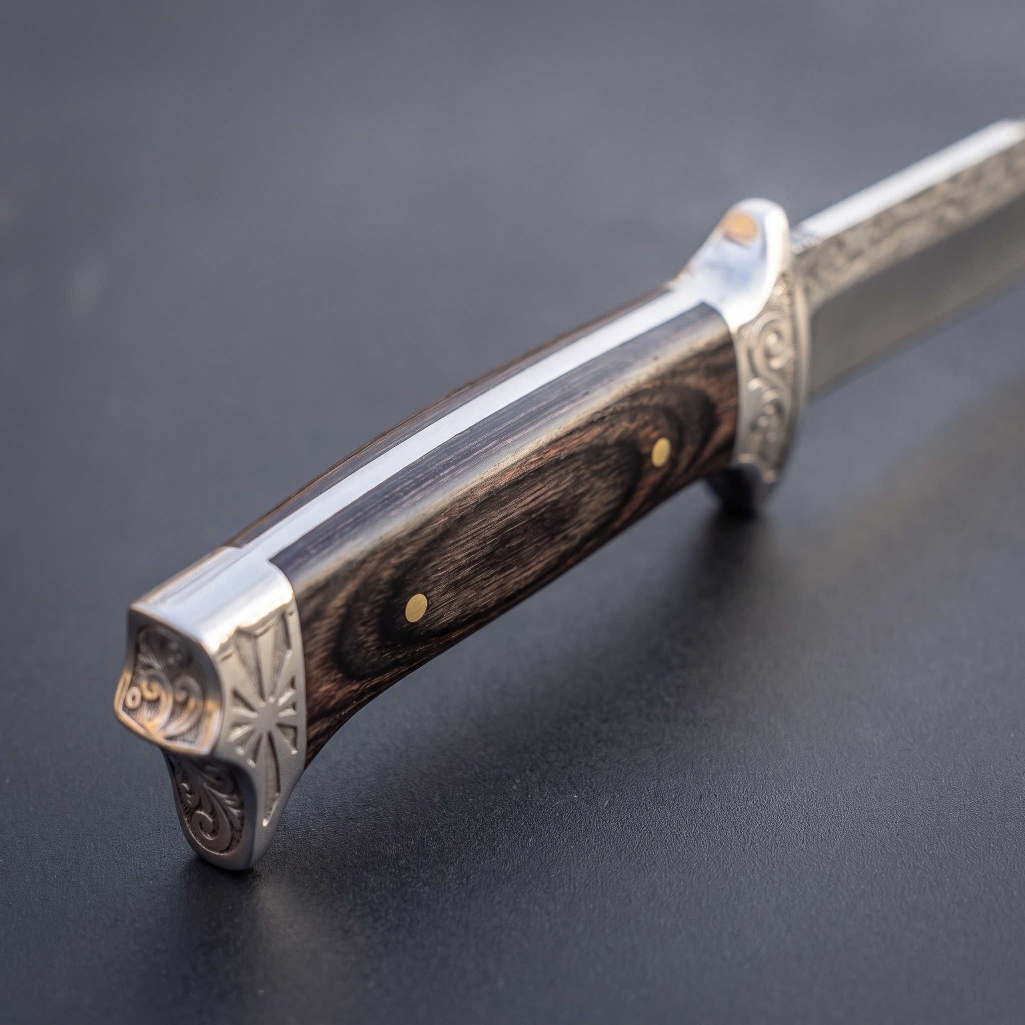 Close-up of the knife's full-tang spine, engraved bolster and wood handle grain